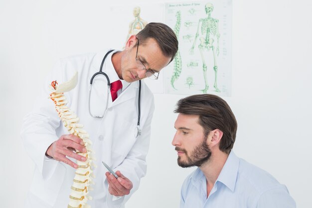 Homme médecin expliquant la colonne vertébrale à un patient