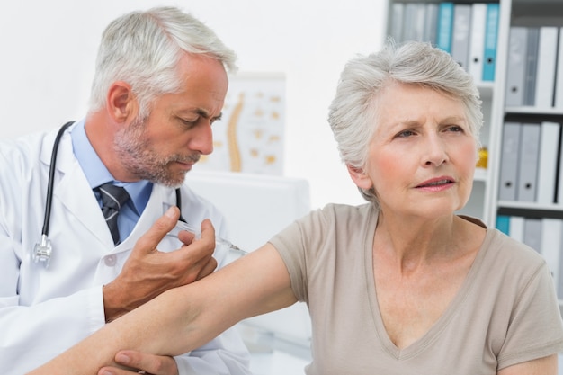 Homme médecin injectant un patient senior