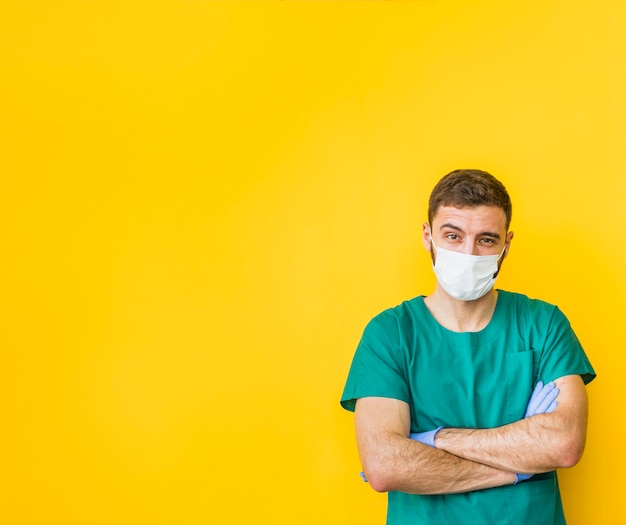 Homme médecin en masque avec les bras croisés