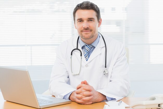 Homme médecin avec ordinateur portable au bureau dans le cabinet médical