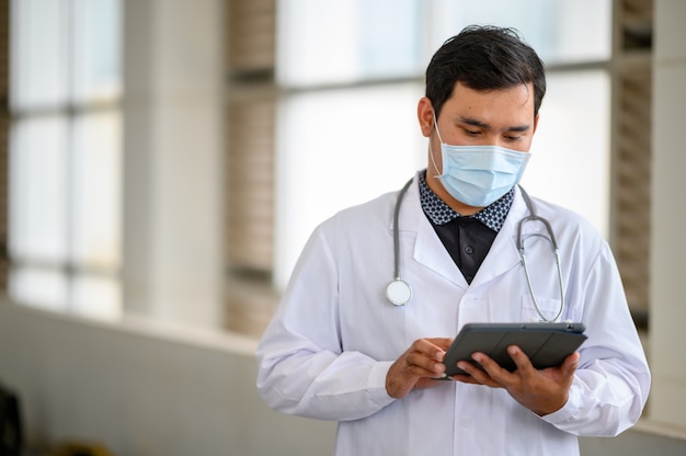 Homme médecin portant un masque et regardant la tablette