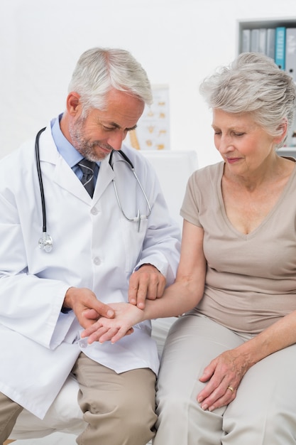 Homme médecin prenant un pouls féminin senior