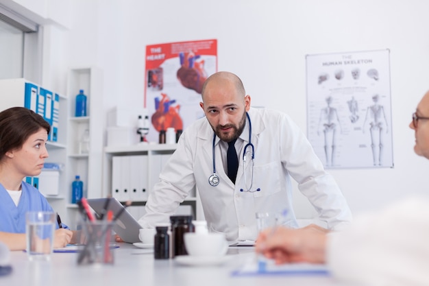 Homme médecin radiologue expliquant les soins de santé au travail d'équipe médicale tout en se tenant au bureau dans la salle de réunion de la conférence