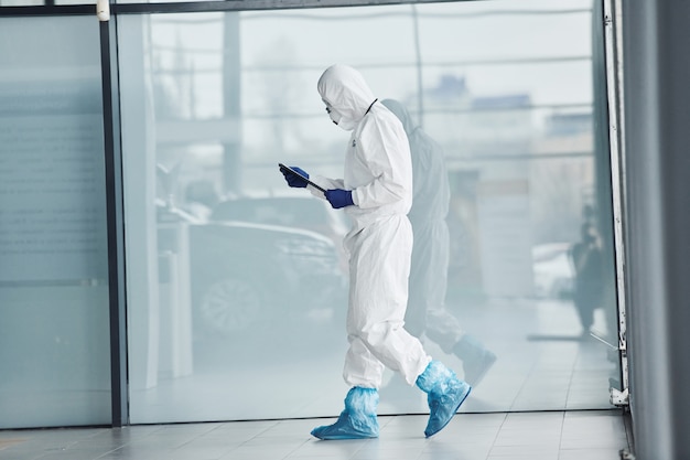 Homme médecin scientifique en blouse de laboratoire, lunettes défensives et masque tenant le bloc-notes dans les mains