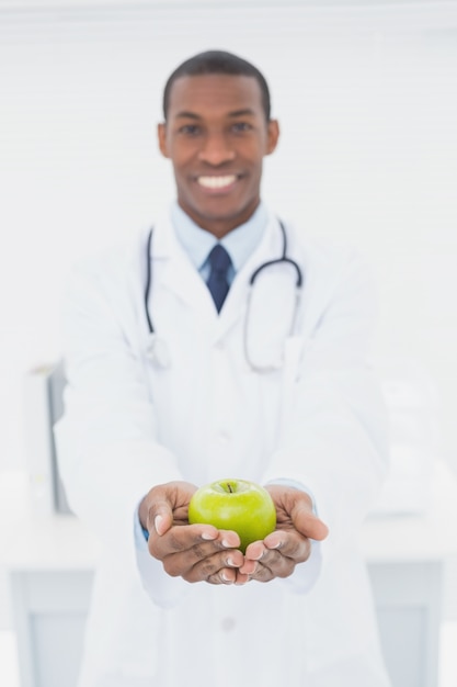 Homme médecin tenant une pomme verte au cabinet médical