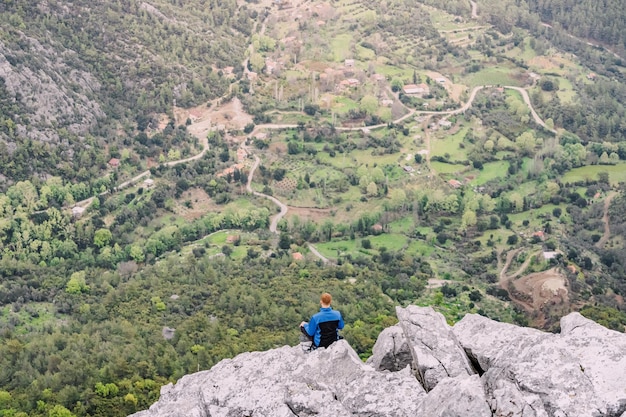 Homme méditant dans la pose de yoga de lotus au sommet de la falaise de montagne surplombant la vue panoramique