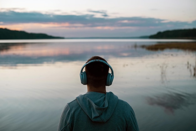 Un homme médite avec des écouteurs dans la nature Il écoute de la musique calme et agréable avant