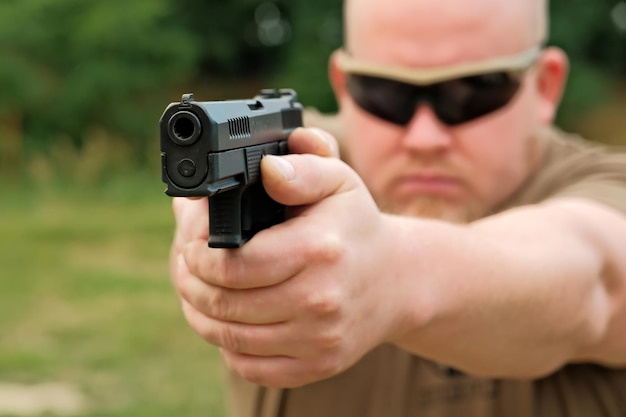 Un homme menace avec un pistolet de combat un homme tenant une arme à feu dans ses mains