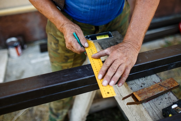 Homme mesurant une barre de métal en atelier.