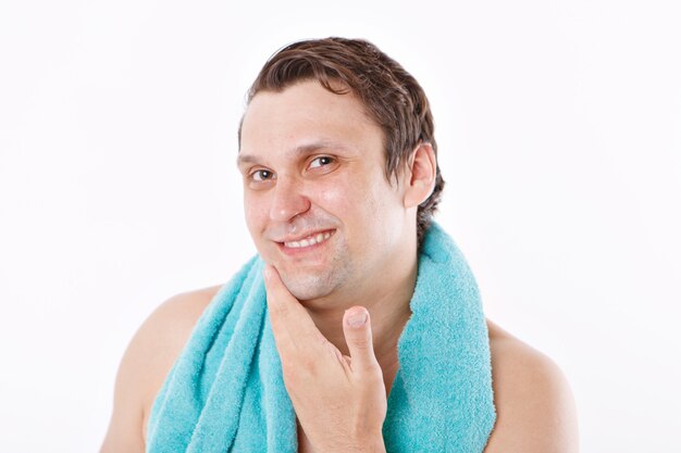 Un homme met un après-rasage sur son visage. le mec lui caresse le visage. soins du matin dans la salle de bain. copie espace