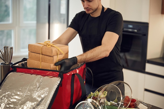 Un homme met des boîtes écologiques en papier dans un sac pour la livraison de nourriture