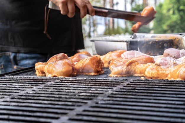 L'homme met du poulet sur le gril pour préparer un dîner en famille dans la cour de la maison