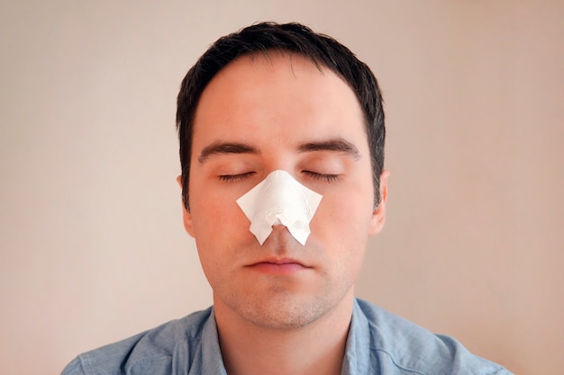 Photo un homme met et enlève une bande pour le nez de points noirs. bandes nettoyantes au charbon des points noirs et des comédons. le concept de soins personnels.