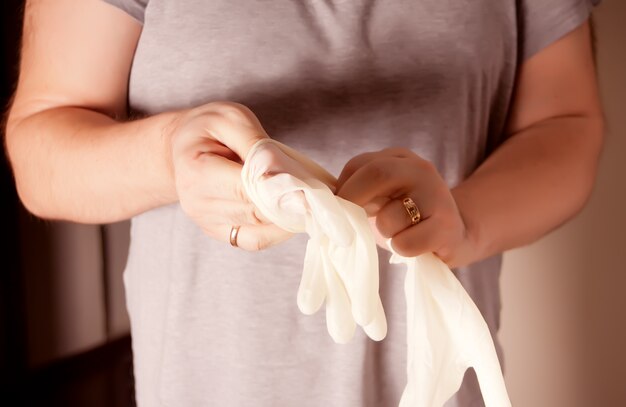 L'homme met des gants de protection en caoutchouc. Protection contre les maladies contagieuses et les coronavirus.