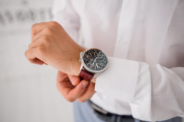 Un homme met une montre sur sa main dans un costume