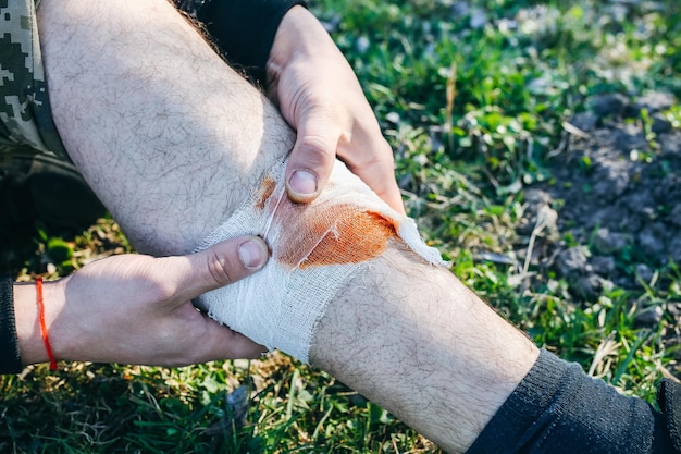 L'homme met un pansement sur une blessure saignante Jambe blessée Touriste dans la nature Danger d'infection Traitement médical Traumatisme de randonnée