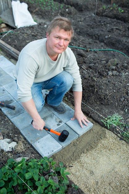 L'homme met le pavage dans le jardin