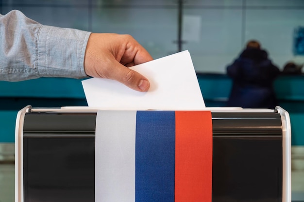 Homme mettant des billuten électoraux dans la boîte lors des élections en russie drapeau de la russie électeurs pour voter un seul jour de vote en Russie dans un bureau de vote