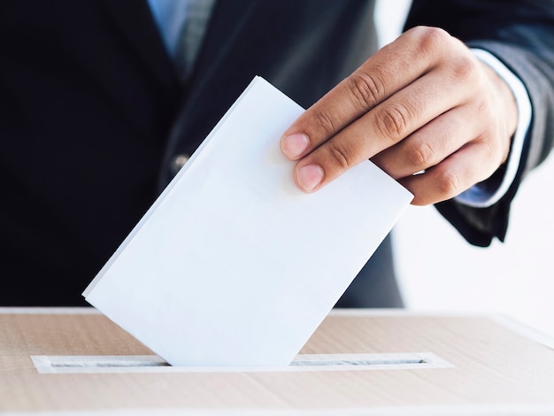Homme mettant un bulletin de vote dans une boîte close-up