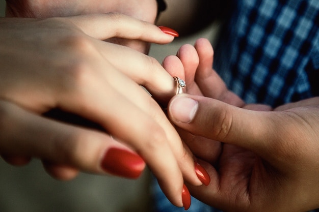 Homme mettant sur close-up de bague de fiançailles de doigt de fille. Copain mettant la bague au doigt de sa copine. Le mâle propose de l'épouser. Bonheur, relations, amour, concept d'engagement. Espace de copie pour le site