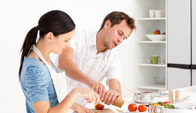 Homme mettant du sel et du poivre pendant que sa copine prépare la sauce