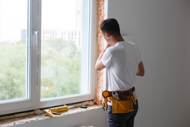 Homme mettant le remplissage entre la fenêtre et le mur dans une nouvelle maison