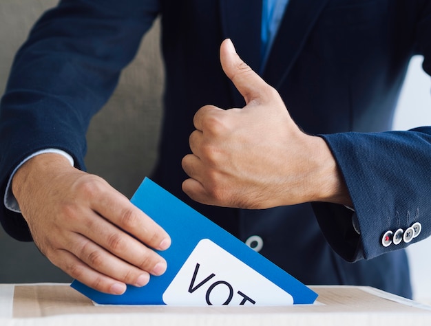 Photo homme mettant son bulletin de vote dans une boîte