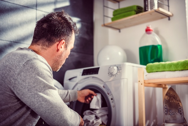 Homme mettant des vêtements dans une machine à laver