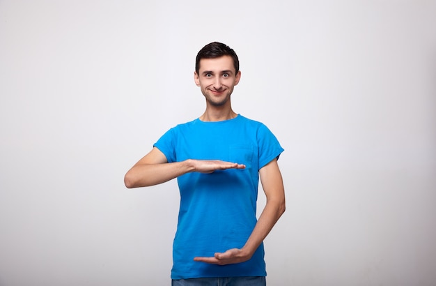 Un homme mignon c dans un T-shirt bleu montre la taille de quelque chose.