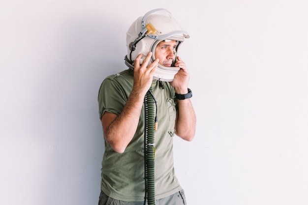 Homme militaire avec casque de cosmonaute astronaute, sur un mur blanc