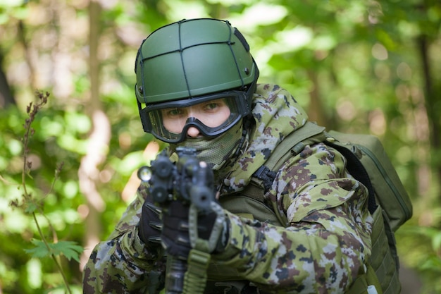 Homme militaire dans les bois avec une mitrailleuse. Préparer l'armée aux hostilités. La mitrailleuse vise