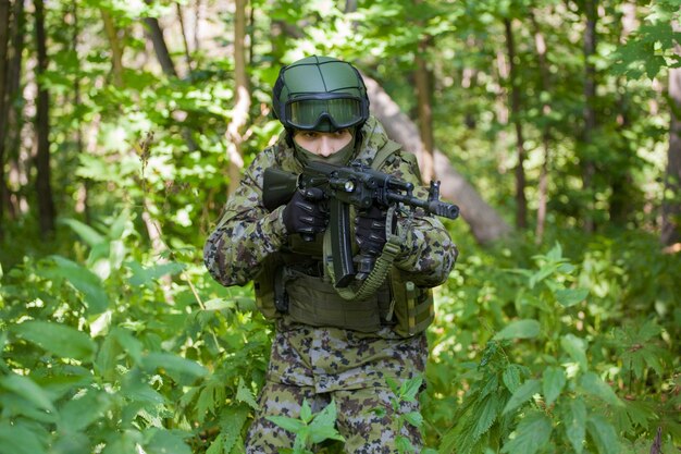 Homme militaire dans les bois avec une mitrailleuse. Préparer l'armée aux hostilités