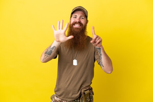 Homme militaire rousse avec dog tag isolé sur fond jaune comptant six avec les doigts