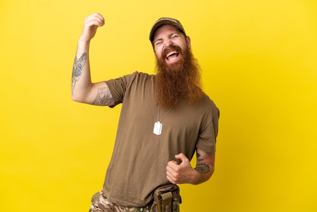 Homme militaire roux avec dog tag isolé sur fond jaune faisant un geste de guitare