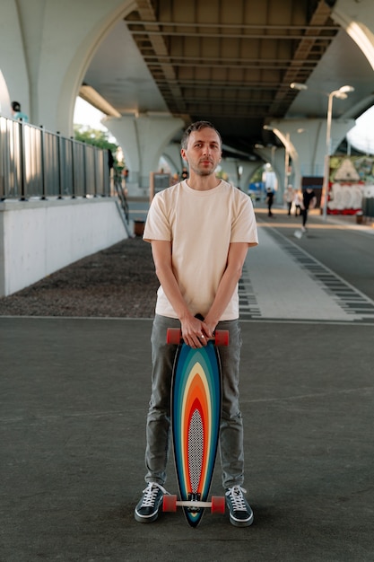 Un Homme Millénaire Tient Une Planche à Roulettes Ou Un Longboard à L'intérieur Dans Un Espace Urbain Pour Des Entraînements De Patinage Extrême