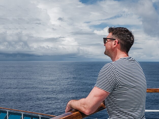 Homme à la mode sur le pont vide d'un paquebot de croisière contre les vagues de la mer