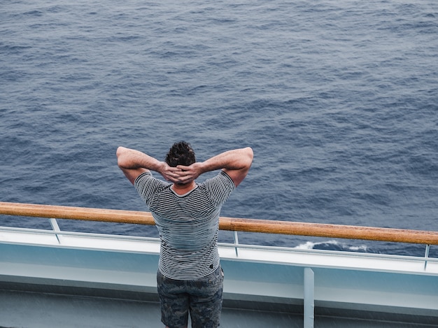 Homme à la mode sur le pont vide d'un paquebot de croisière contre les vagues de la mer