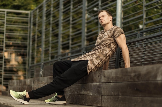 Homme modèle musclé en t-shirt kaki sur fond de gym en plein air