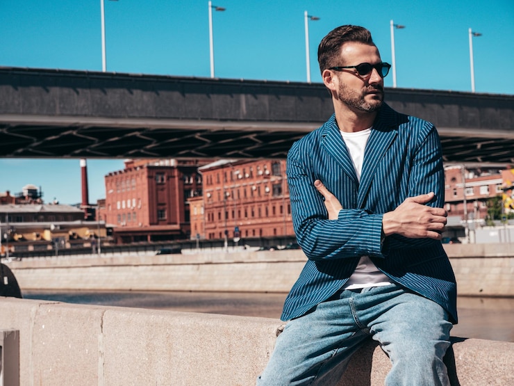 Photo un homme moderne sexy vêtu d'un élégant costume bleu et de jeans un homme à la mode posant sur le fond de la rue