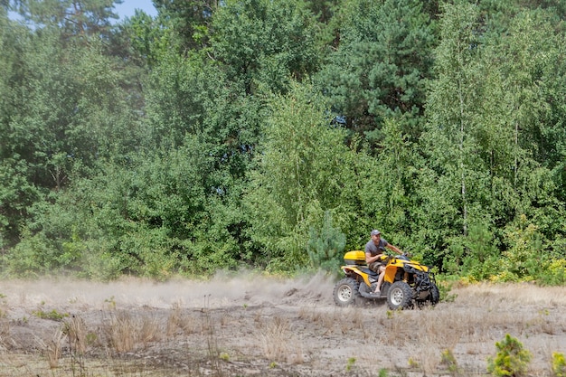 Homme monté sur un véhicule tout-terrain quad quad jaune sur une forêt de sable