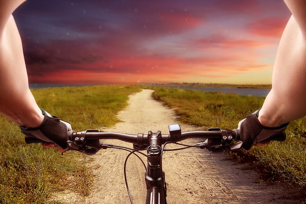 Homme monté sur un vélo au coucher du soleil