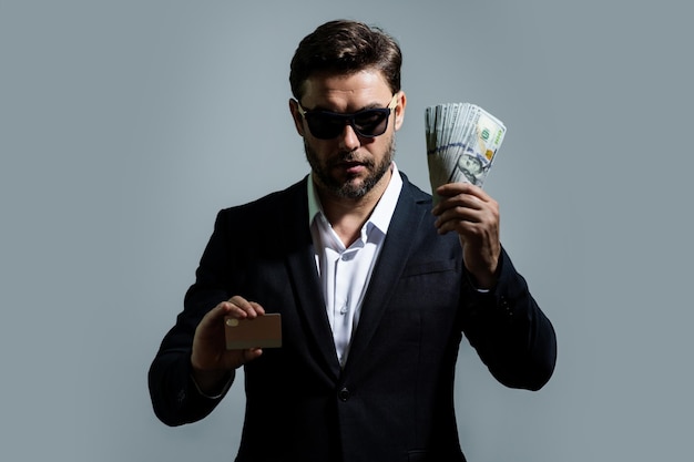 Homme montrant de l'argent en espèces en billets de dollar portrait d'un homme d'affaires isolé sur un studio gris