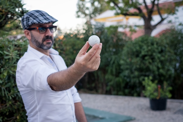 homme montrant une balle de golf dans ses mains