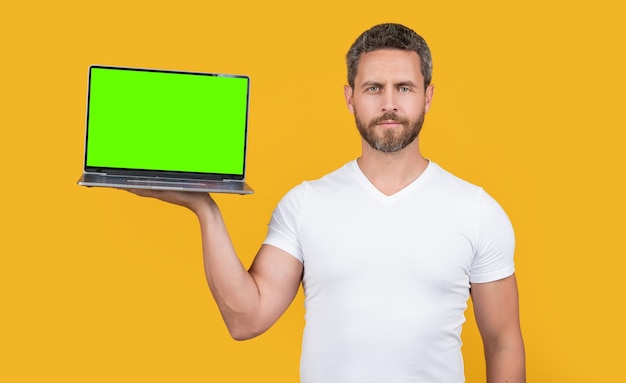 Homme montrant un ordinateur portable isolé sur fond jaune homme présentant un ordinateur portable