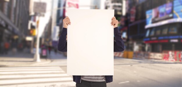 Homme montrant le panneau d'affichage devant le visage contre la rue floue de new york