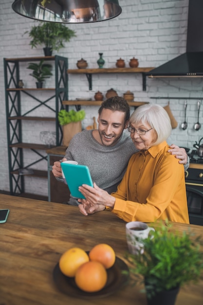 Homme montrant à sa mère comment utiliser la tablette