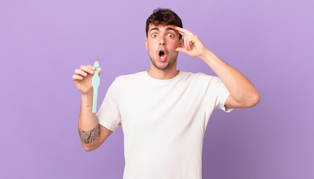 Homme avec une montre ayant l'air surpris, bouche bée, choqué, réalisant une nouvelle pensée, idée ou concept