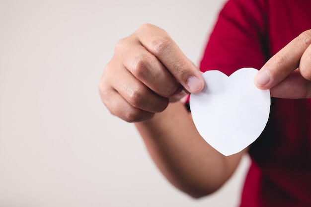 L'homme montre un coeur de papier blanc sur les mains Gros plan avec espace de copie