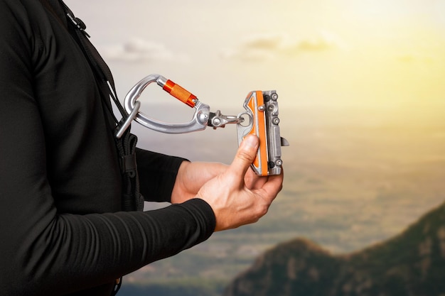 Un homme montre un mécanisme autobloquant Pour la montée et la descente Système d'assurance Télécommunications Pour les travaux en hauteur alpinisme industriel tourisme hauteur En montagne