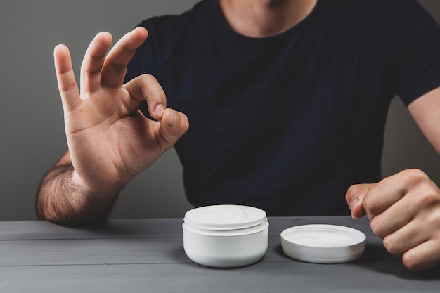 L'homme montre ok assis devant la crème pour les mains